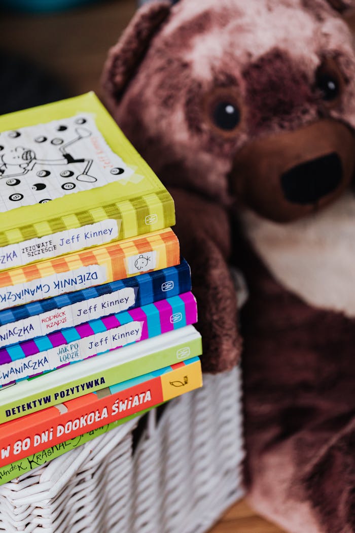 services-02 A stack of colorful children's books next to a cute brown teddy bear.